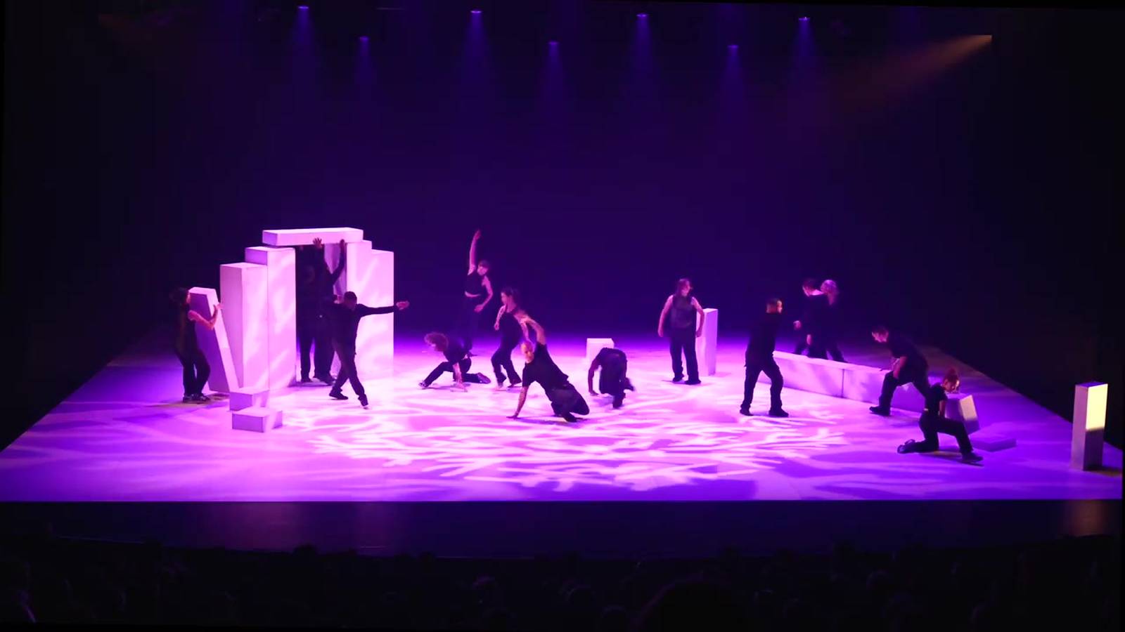 Les danseurs de la compagnie sur un plateau baigné de lumière violette